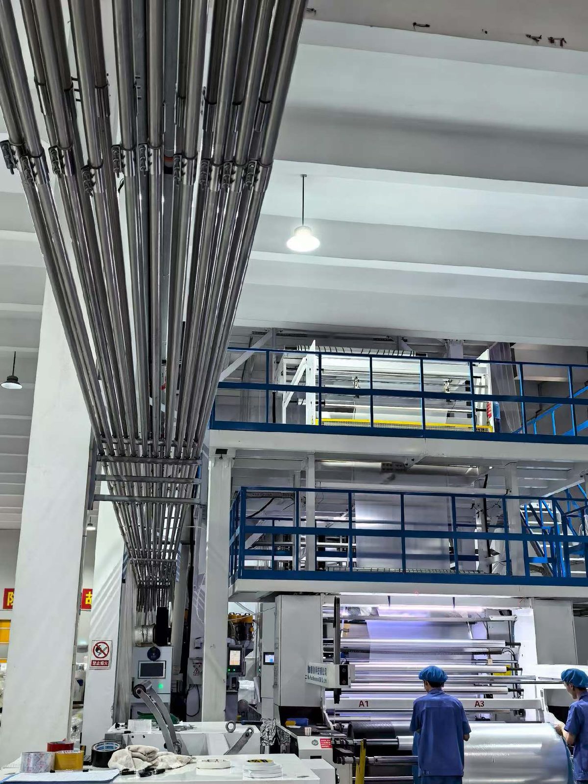 Multi-level film production line with overhead material conveying pipes