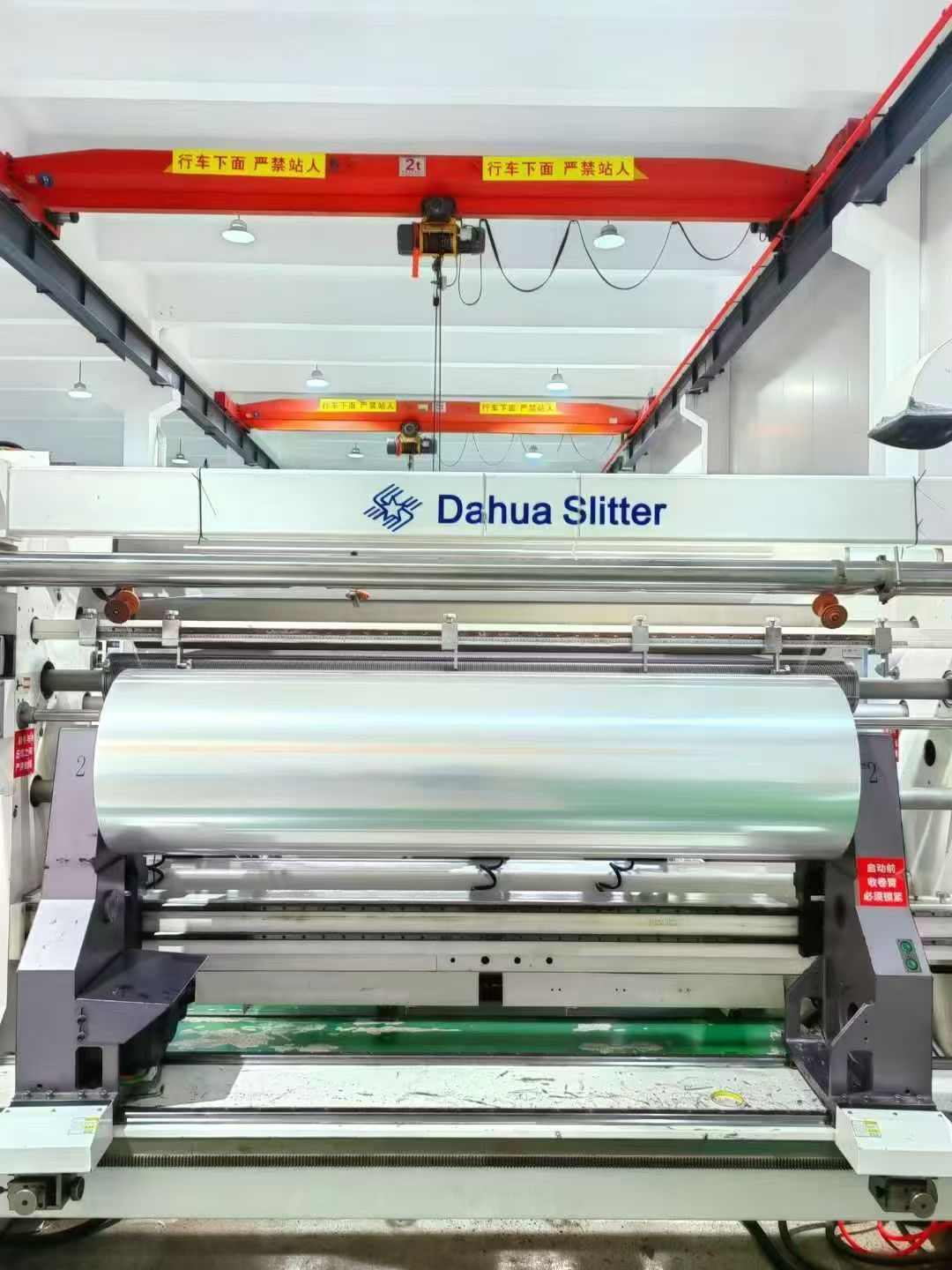 Slitting and rewinding machine with an overhead crane